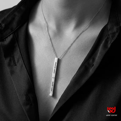 Silver necklace with a pendant on a person wearing a dark jacket.