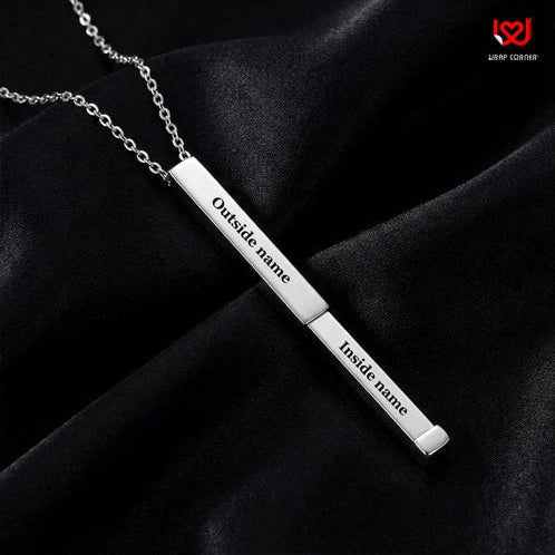 Silver necklace with two engraved nameplates on a black fabric background